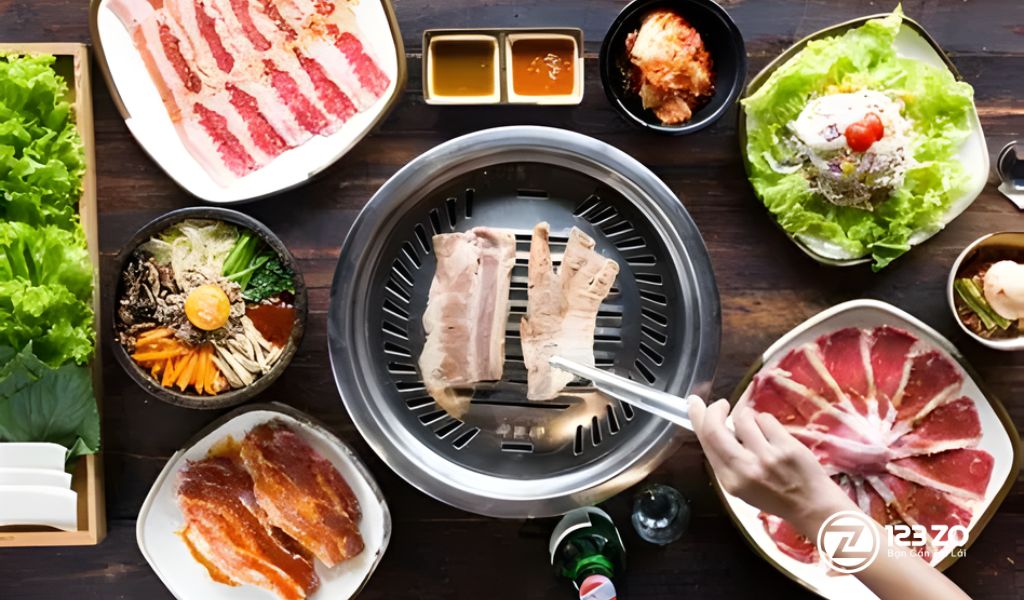Bàn tiệc nướng Hàn Quốc tại GoGi House với thịt ba chỉ, cơm trộn Bibimbap, salad và đồ nướng trên vỉ không khói.