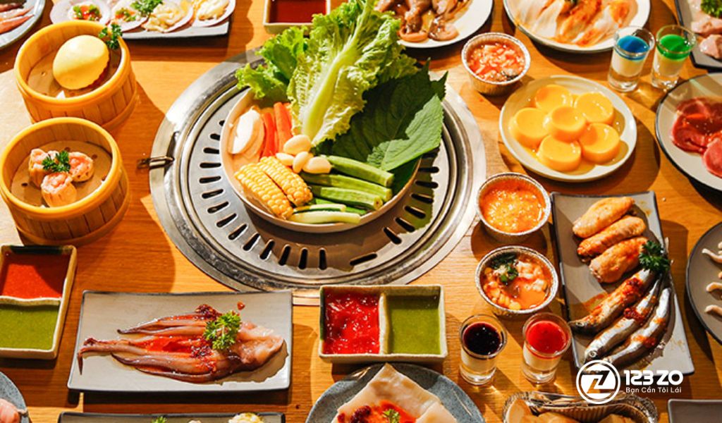 Bàn tiệc Buffet nướng RAKUEN BBQ với thịt, rau xanh, bắp nướng và nhiều loại nước chấm, phục vụ trong không gian Á Đông.