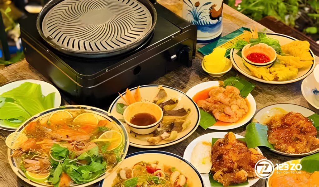 Bàn ăn mộc mạc tại Tiệm Nướng Nhà Bird với lẩu Thái Tomyum và các món nướng được tẩm ướp đặc trưng.