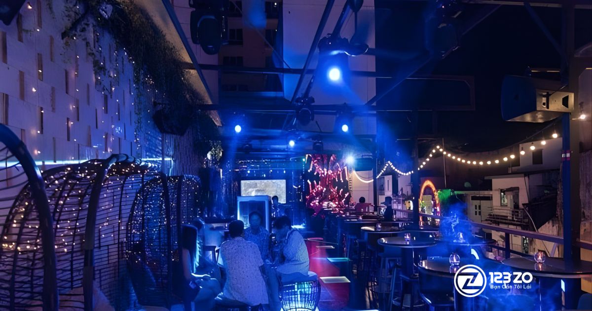 Top 10 quán nhậu, beer club Bùi Viện “hot” nhất Quận 1 2025 5 Quán nhậu, beer club Corner Sky Bar với thiết kế hiện đại, đèn chiếu sáng màu xanh dương, ghế mây và tầm nhìn mở.