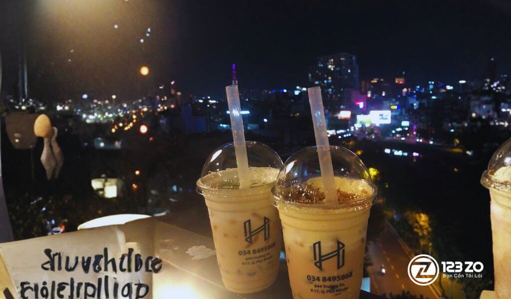 Quán rooftop tại Quận Phú nhuận. Hình ảnh đồ uống của quán, nổi bật trên nền cảnh đêm thành phố rực rỡ ánh đèn, phù hợp cho những cuộc hẹn hò lãng mạn.