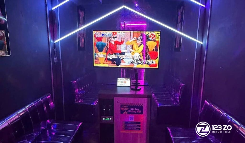 Nội thất phòng hát hiện đại, tông màu xanh dương đậm và đen, với đèn LED hình học sáng tạo tại quán karaoke Kaka Music Box Bình Thạnh.
