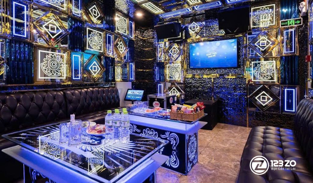 Nội thất phòng hát hiện đại, tông màu xanh ngọc và đen, với đèn trần pha lê tại quán karaoke Louis KT Bình Thạnh.