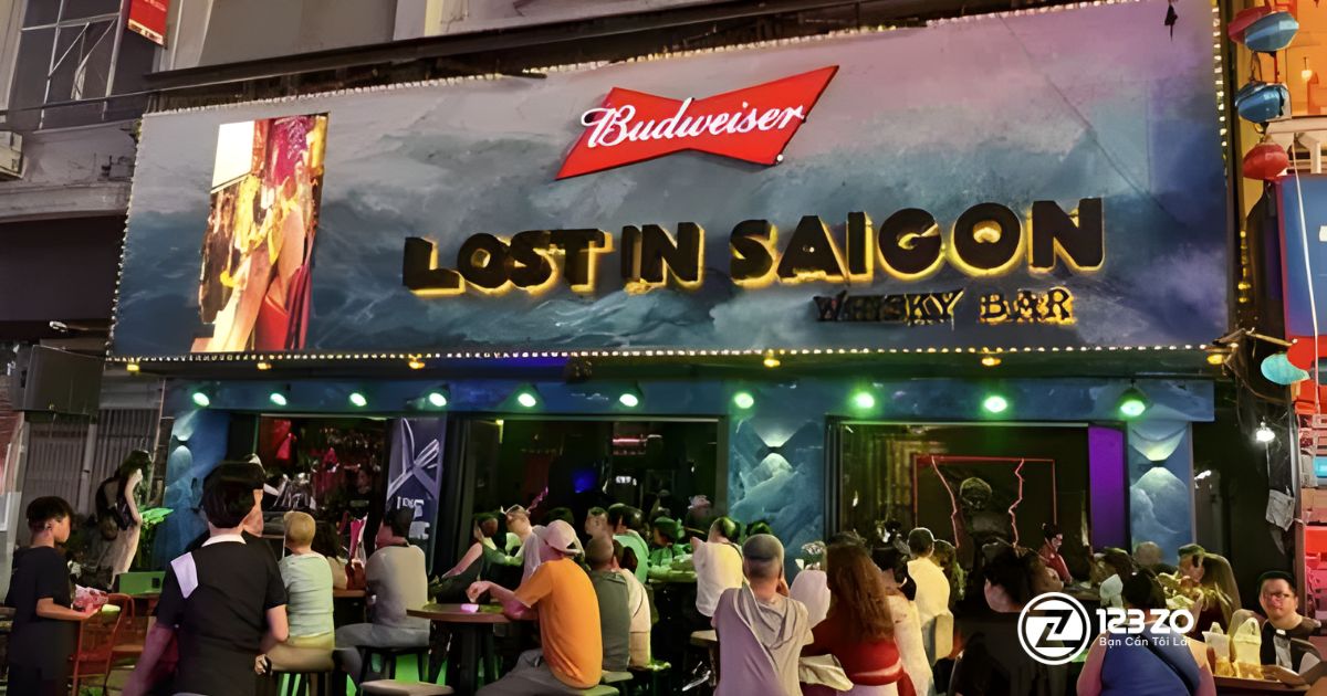 Top 10 quán nhậu, beer club Bùi Viện “hot” nhất Quận 1 2025 4 Quán nhậu, beer club LOST IN SAIGON WHISKY BAR với hình ảnh sóng nước và logo Budweiser, cùng đám đông khách ngồi ở mặt tiền.