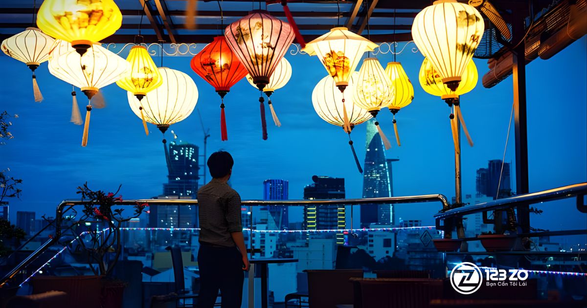 Top 10 quán nhậu, beer club Bùi Viện “hot” nhất Quận 1 2025 3 Khung cảnh hoàng hôn tại The View Rooftop Bar, với đèn lồng truyền thống treo phía trên và một người đàn ông đang ngắm nhìn đường chân trời thành phố (có tòa nhà Bitexco).