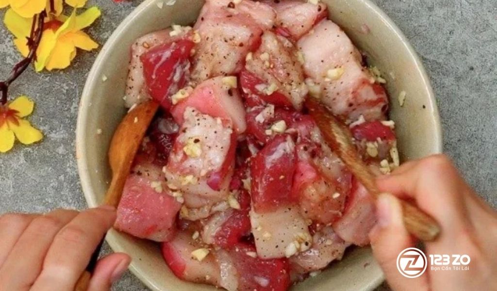 Hình ảnh ướp thịt ba chỉ với gia vị (tỏi, tiêu) để thấm đều vị trước khi kho. Bí quyết cho Thịt Kho Hột Vịt thơm ngon.